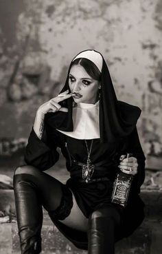 a woman sitting on the ground with a bottle of booze next to her face