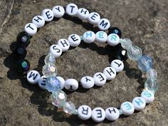 two bracelets with words on them sitting on top of a rocky surface next to each other