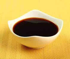 a white bowl filled with black liquid on top of a yellow cloth covered tablecloth