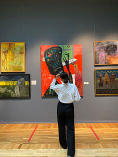 a woman is looking at paintings on the wall