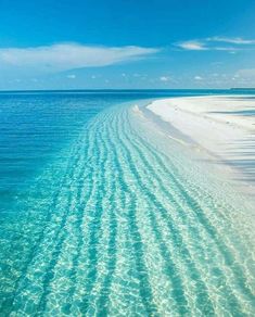 the water is crystal blue and clear with white sand on it's sides, as well as an island in the distance