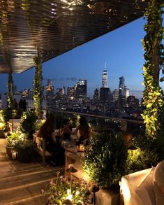 people sitting at tables on top of a roof with the city skyline in the background