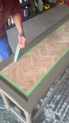 a person is using a knife to paint a herringbone pattern on a table