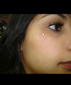 a close up of a woman's face with an ear piercing on her nose