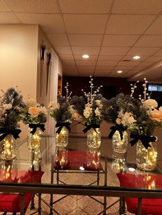 four vases with flowers are sitting on a table in front of a mirror and red chairs