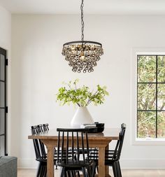 a chandelier hanging from the ceiling over a dining room table with black chairs