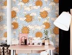 a desk with a lamp on top of it next to a wallpapered background