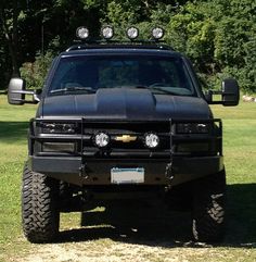 a black truck parked on top of a lush green field