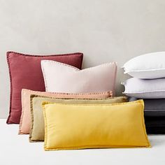 four pillows stacked on top of each other in different colors and sizes, along with one pillow