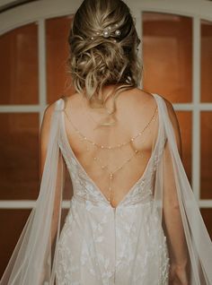 the back of a bride's dress with a veil over her shoulder and beaded headpiece