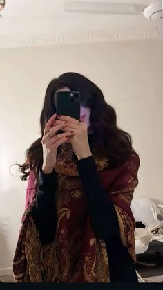 a woman taking a selfie with her cell phone in front of her face and wearing a scarf around her neck