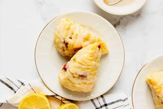 two plates with pastries on them next to lemon slices