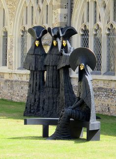 two black statues sitting on top of a bench