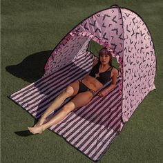 a woman laying in a pink and black tent