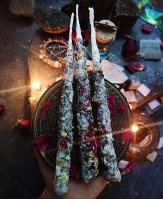 a person holding some kind of food on a plate with candles in the back ground