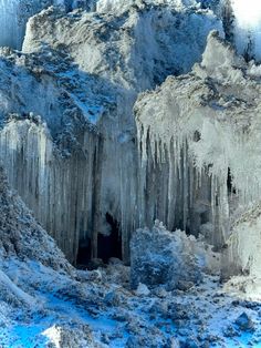 an ice cave with icicles hanging from it's sides and snow on the ground