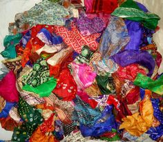 a large pile of colorful scarves sitting on top of a white sheet covered floor