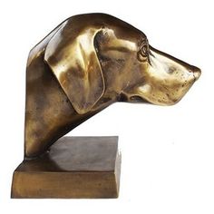 a bronze sculpture of a dog's head on top of a wooden block in front of a white background