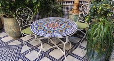 an outdoor table and chairs with potted plants in the background