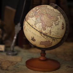 an old world globe sitting on top of a wooden stand