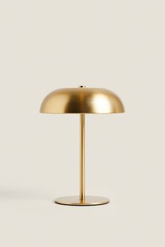 a gold table lamp on a white surface with the light turned off to show its dim lighting