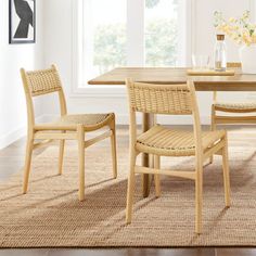 a dining room table and chairs in front of a window with flowers on the rug