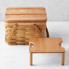 a wooden bench and basket sitting on a table next to each other, with the lid open