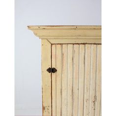 an old wooden cabinet with two knobs on the front and side doors, against a white wall