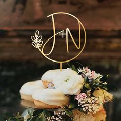 there is a cake with flowers on it and a monogram topper in the middle