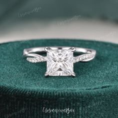 a princess cut diamond engagement ring on top of a green velvet box