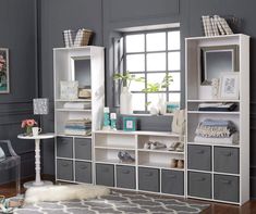 a living room with blue walls and white shelving units on the wall, along with a gray rug