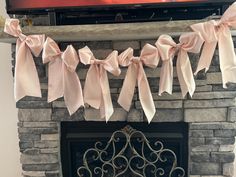 the fireplace is decorated with pink ribbon and bows