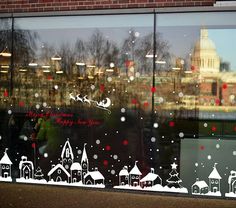 the window is decorated with white and red christmas decorations, including santa's sleighs