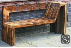 a wooden bench sitting next to a brick wall