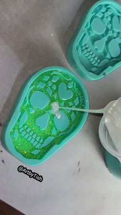 two plastic skull molds with green glitter on them