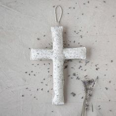 a white cross ornament next to scissors on a gray surface with black speckles