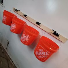 four red buckets hanging on a wall with the words the home depot written on them