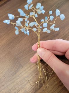 a hand holding a wire tree with blue glass beads