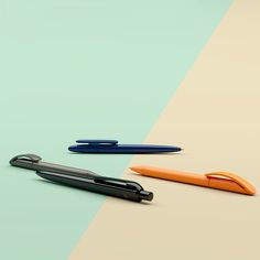 three different colored pens sitting next to each other on top of a green and blue surface