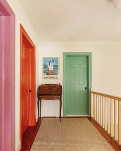 a hallway with two doors and a table in the corner next to it on top of a carpeted floor