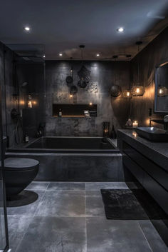 a modern bathroom with black walls and flooring is lit up by the lights on the ceiling