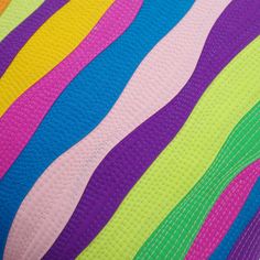 a close up view of a quilt made with multicolored strips on the fabric