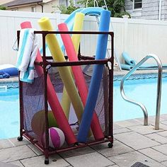 an outdoor pool with a basket full of colorful balls and tees next to a swimming pool