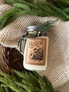 a candle sitting on top of a table next to pine branches