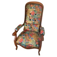 an upholstered chair with floral fabric and wood trimmings on the back