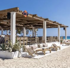 an outdoor seating area on the beach with chairs and tables