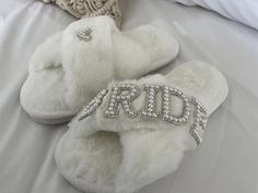 a pair of white slippers sitting on top of a bed next to a pillow