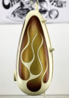 an egg shaped object is sitting on a stand in front of a white wall with black and gold designs