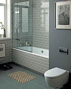 a white toilet sitting next to a bath tub in a bathroom with gray walls and floor