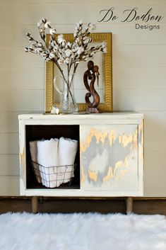 a white cabinet with some flowers and towels in it on top of a fur rug